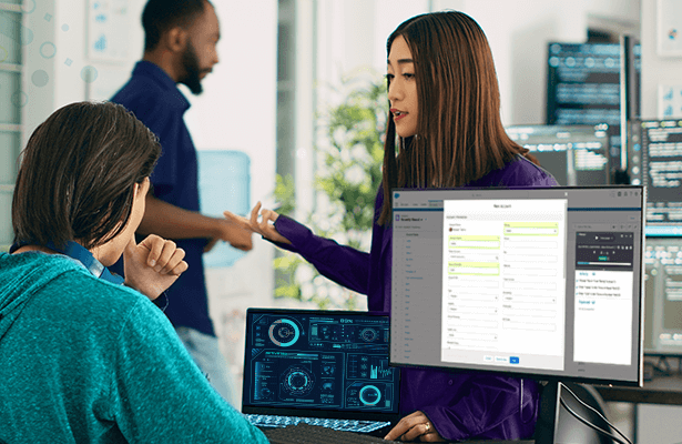 A team working on a business solution with dashboards open on the computer screen